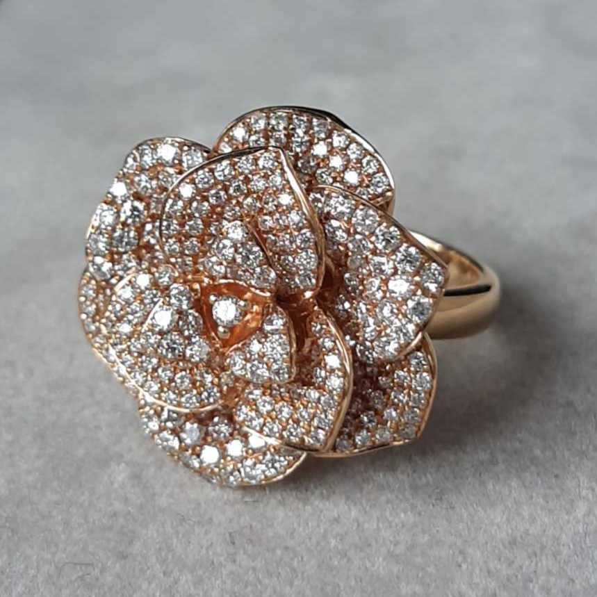 Bague fleur en or rose 18K et diamants, une création d’exception où la joaillerie devient art. Chaque pétale, serti d’un pavage minutieux, capture la lumière avec une douceur subtile et révèle un éclat vibrant. Alliance rare de virtuosité technique et de poésie joaillière, cette pièce iconique célèbre la beauté intemporelle de la nature sublimée par la main de l’artisan.