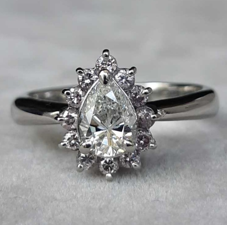 Bague en platine, diamant taille poire — l’élégance du juste milieu, mi-chemin entre solitaire et marguerite, cette création marie la pureté d’un diamant taille poire de 0,72 ct à l’éclat d’un entourage délicat de brillants. Ses proportions harmonieuses et son dessin classique en font une pièce emblématique et intemporelle.