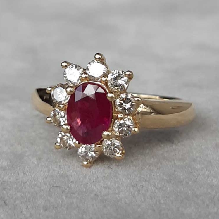 Bague marguerite en or jaune 18K, centrée d’un rubis naturel de forme ovale, entouré de diamants naturels taillés brillant.