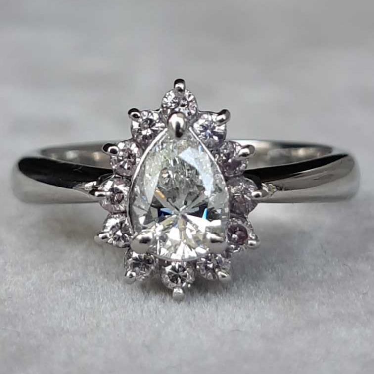 Solitaire marguerite en platine centrée d’un diamant de taille poire de 0,72 ct, entouré de diamants taillés brillants.